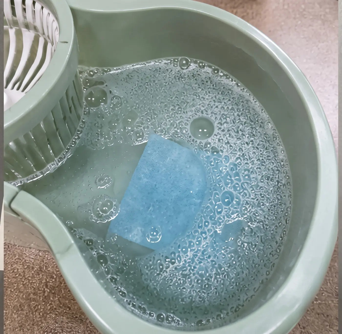 Blue floor cleaning sheet dissolving in a mop bucket