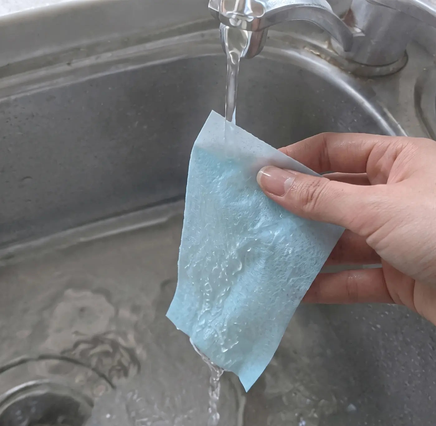 Customer holding a blue cleaning sheet under running water