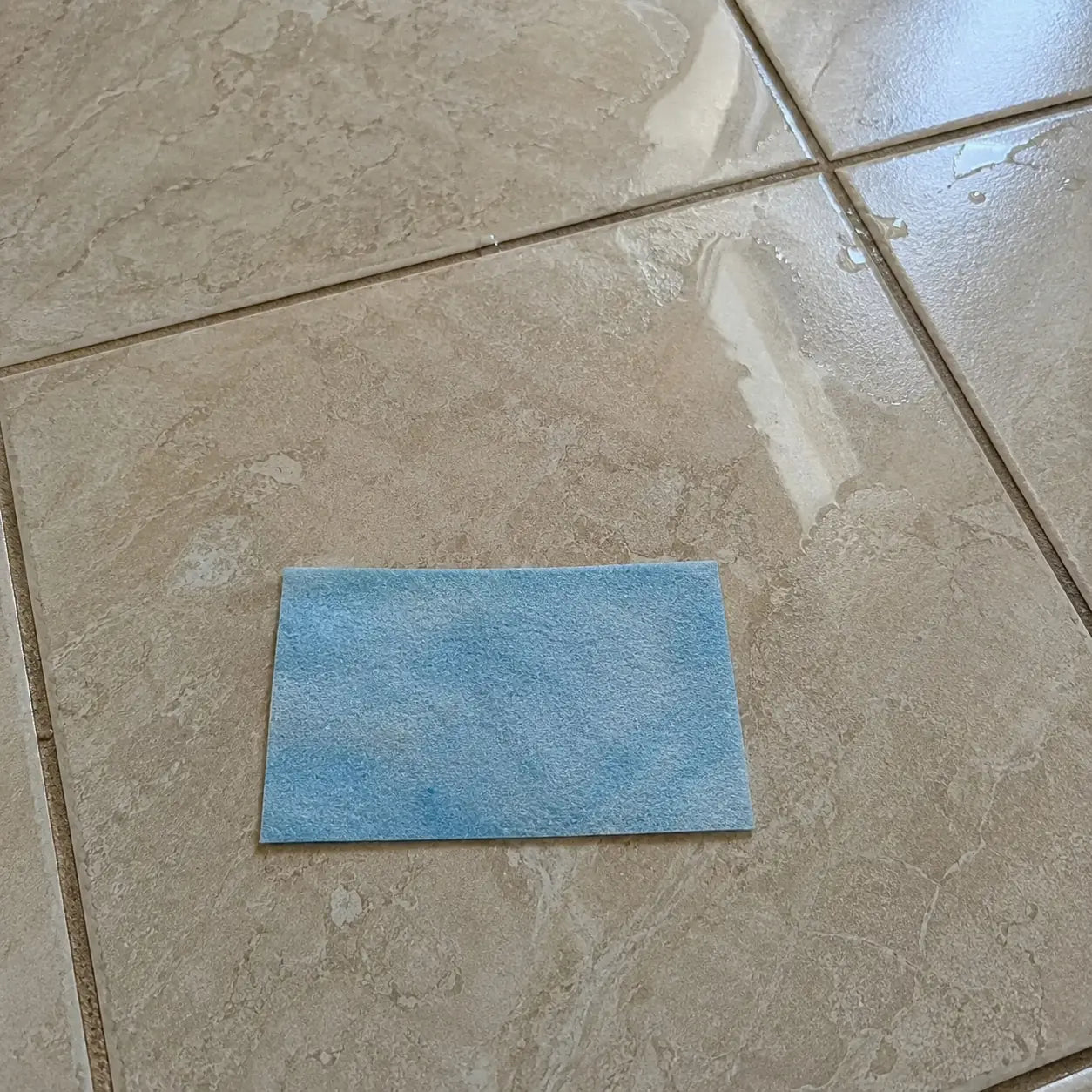 Blue floor cleaning sheet placed on a tiled floor