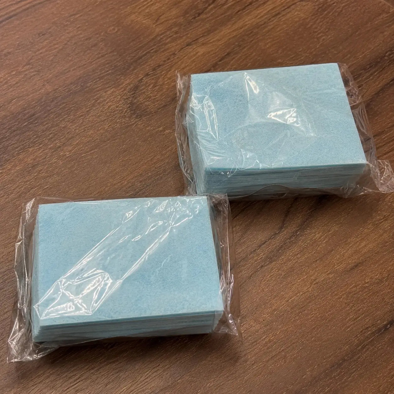 Two compact stacks of blue floor cleaning sheets