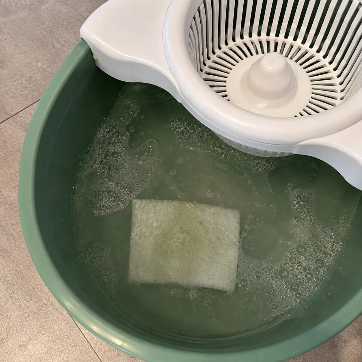 Floor cleaning sheet dissolving in green mop bucket